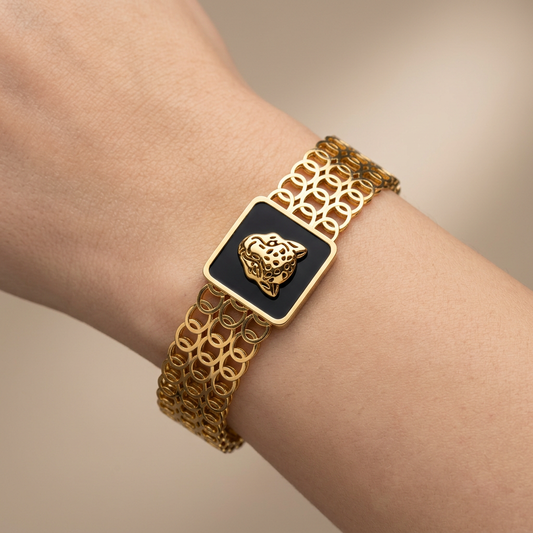 Bracelet manchette doré tête de léopard porté au poignet, photo studio