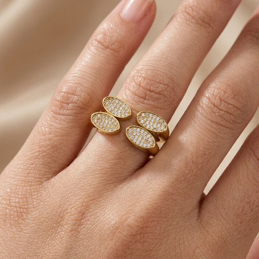 Bague dorée à feuilles et cristaux portée au doigt